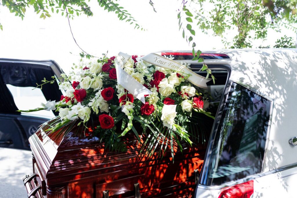Casket With Red Roses In The Back Of A Hearse