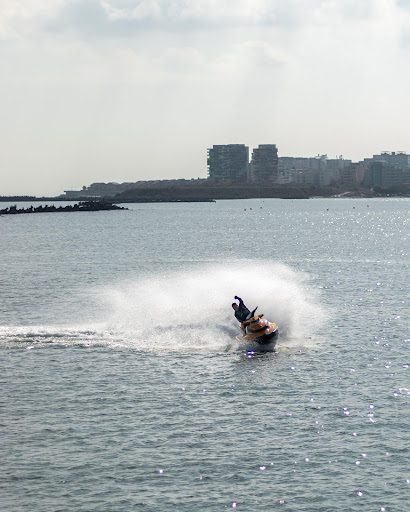Person Riding A Jet Ski Near A City Shoreline