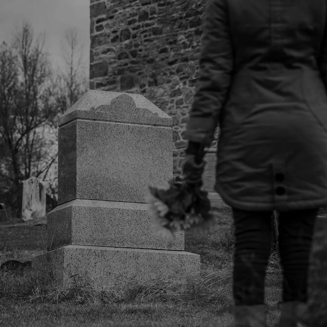 Person Standing Beside A Cemetery Headstone